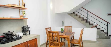 A modern kitchen with wooden cabinets, a gas stove, and a dining area with wooden chairs and a table.