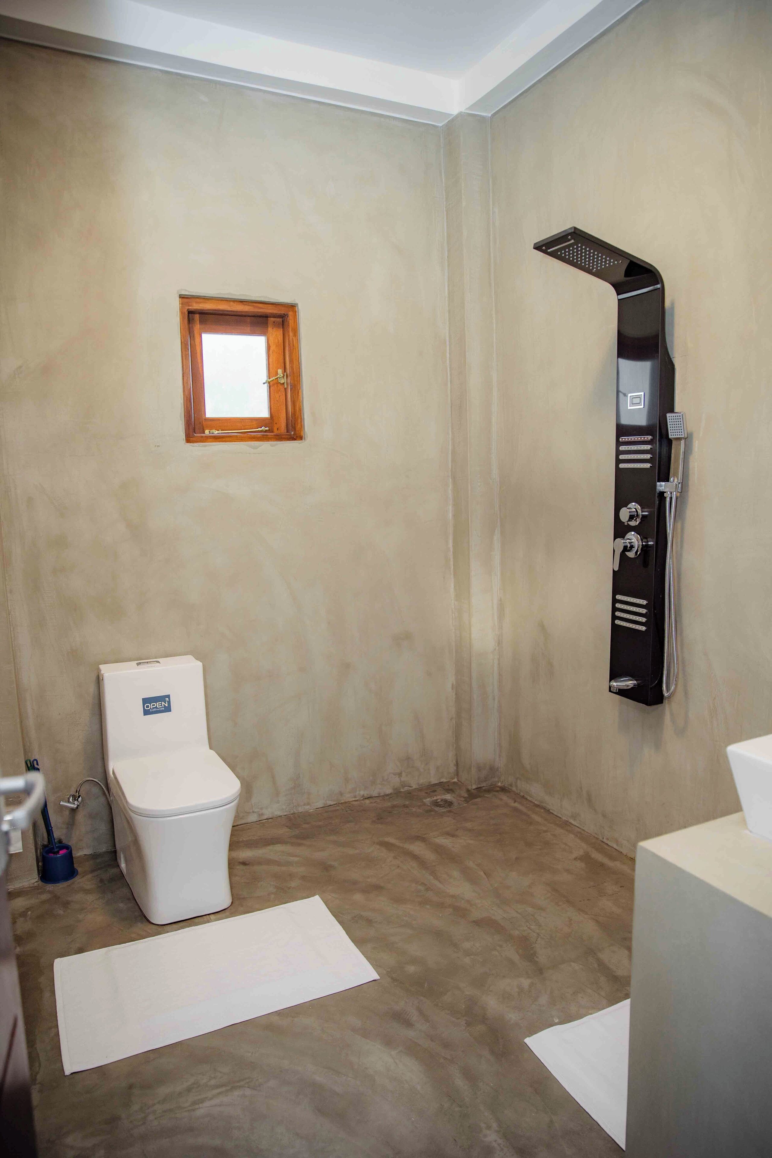 A bathroom with a toilet, a shower, and a small window.