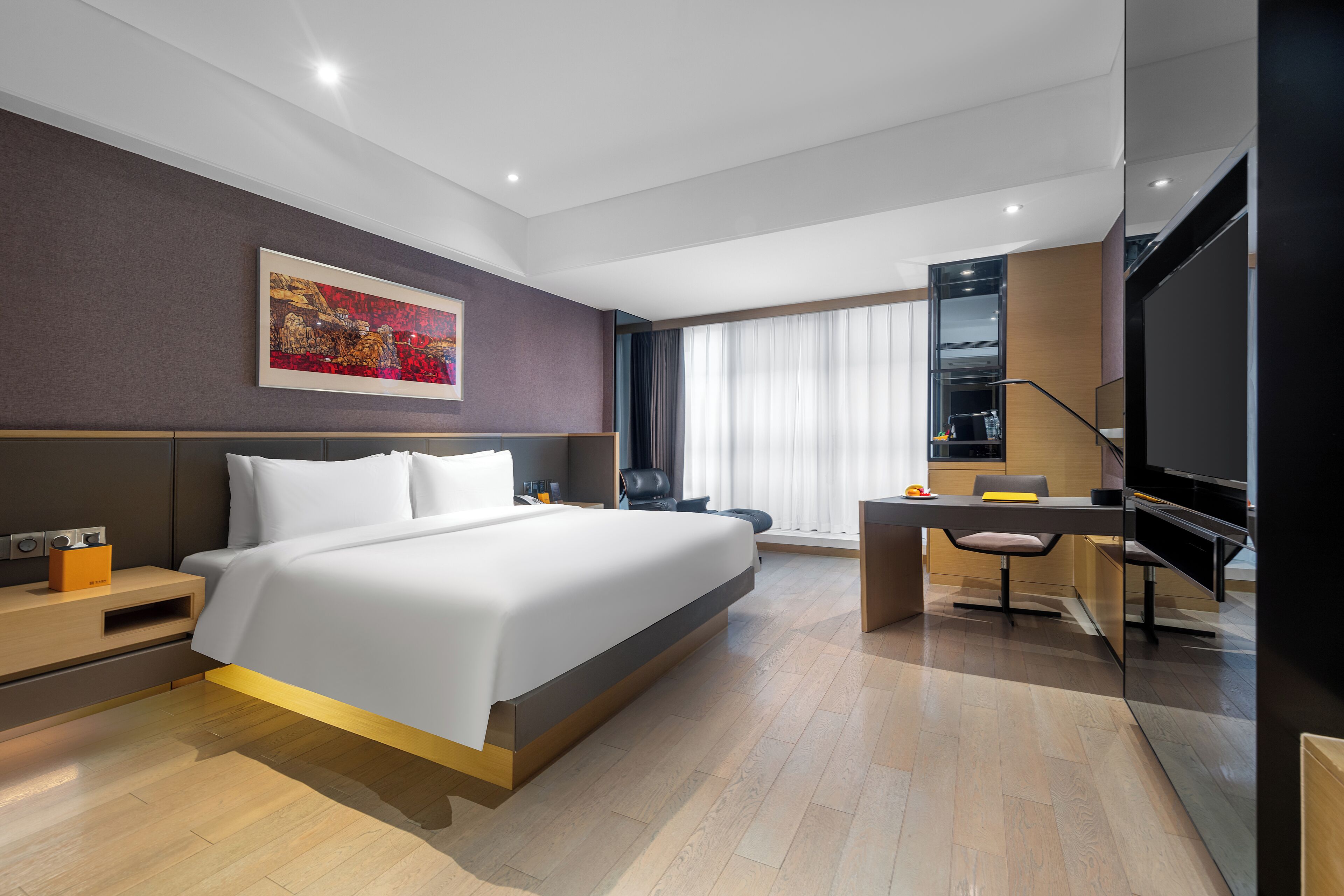 A modern hotel room with a large bed, a desk, and a television.