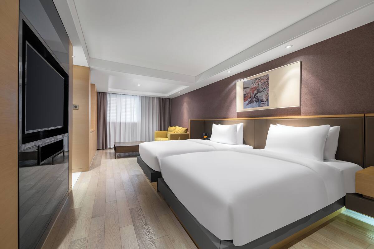 Une chambre d’hôtel moderne, dotée d’un grand lit, d’une télévision à écran plat, d’un canapé et d’un tableau au mur.