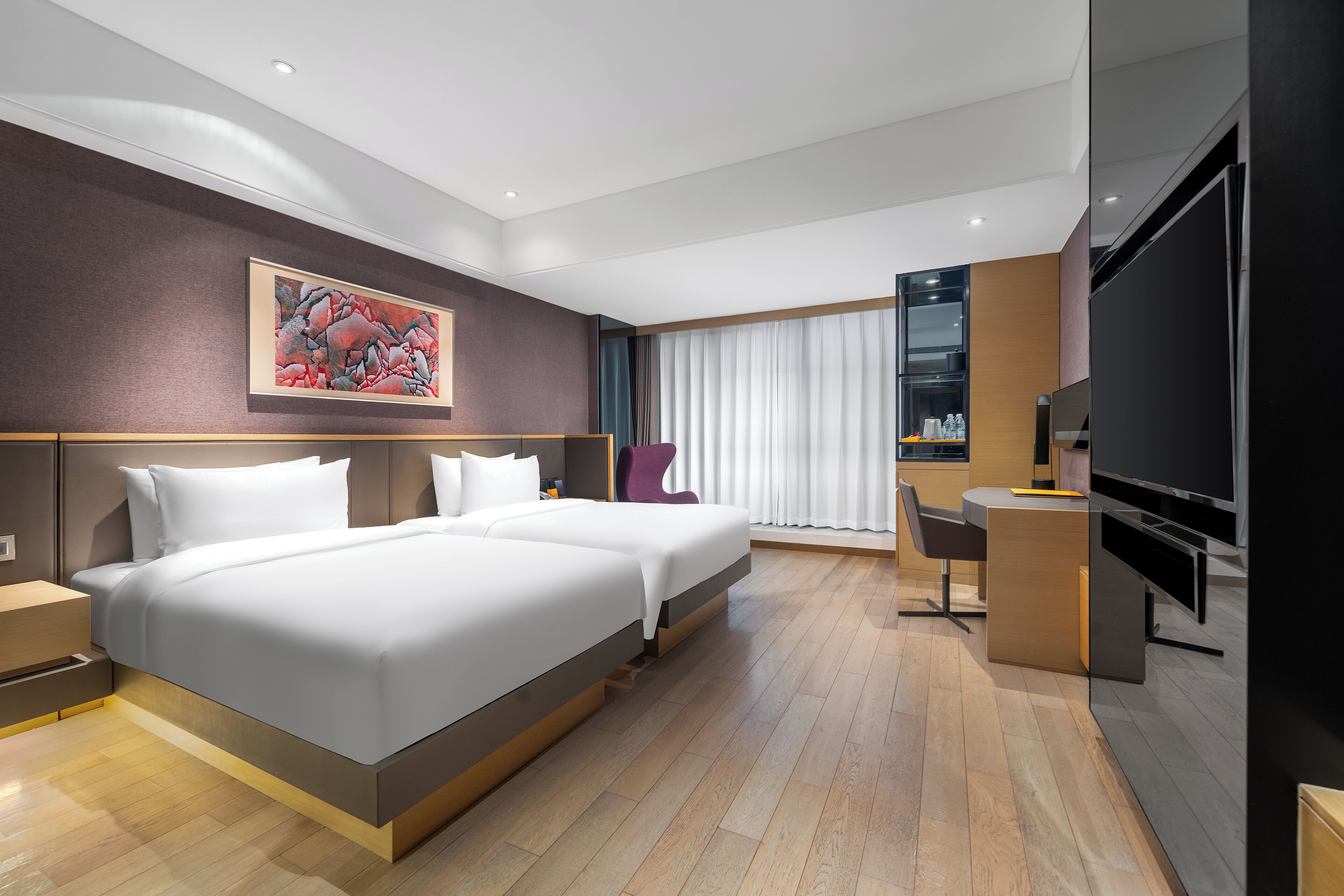 Una habitación de hotel moderna con dos camas, un escritorio, un televisor y un ventanal con cortinas.