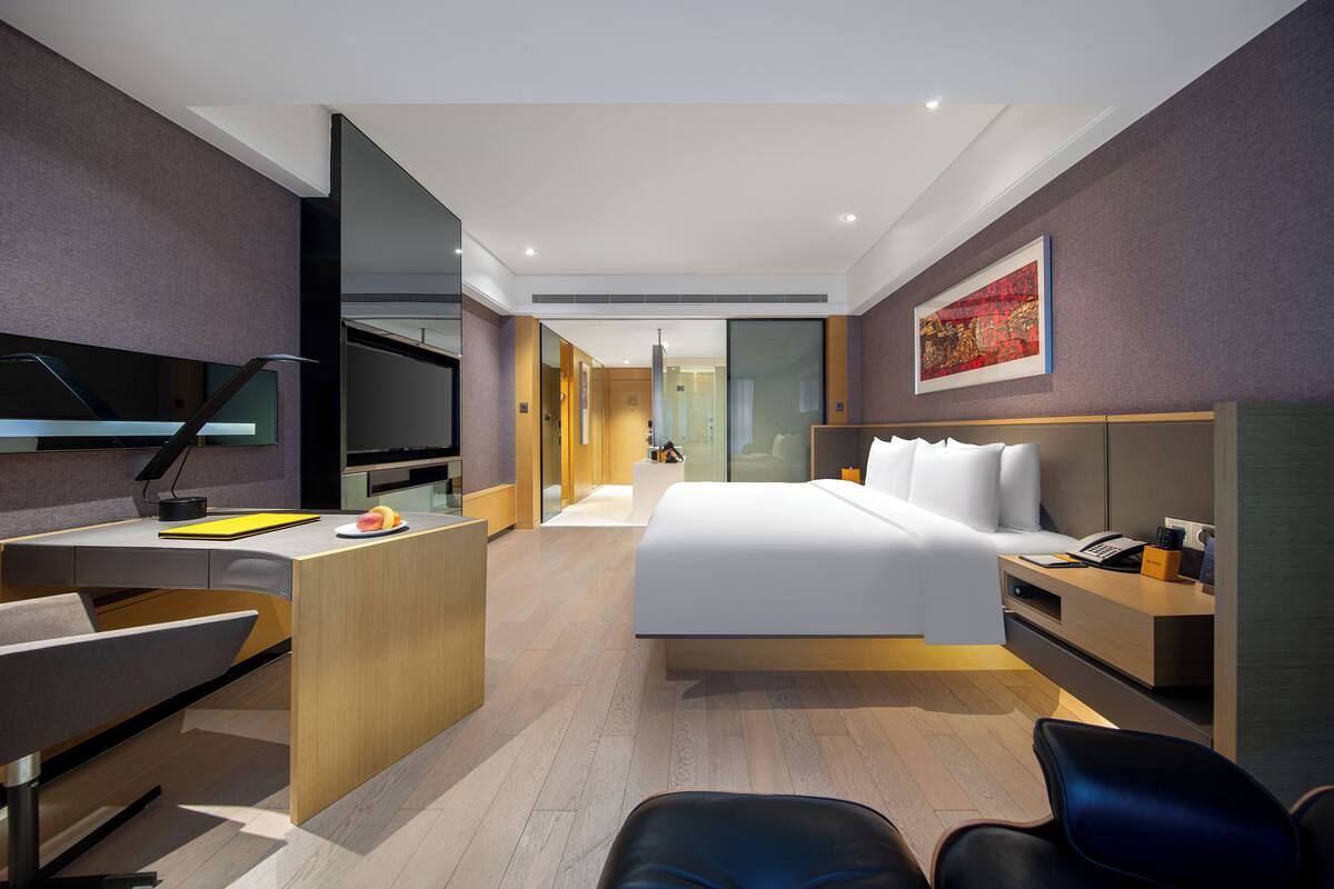 Une chambre d’hôtel moderne équipée d’un lit, d’un bureau, d’une chaise et d’un téléviseur.
