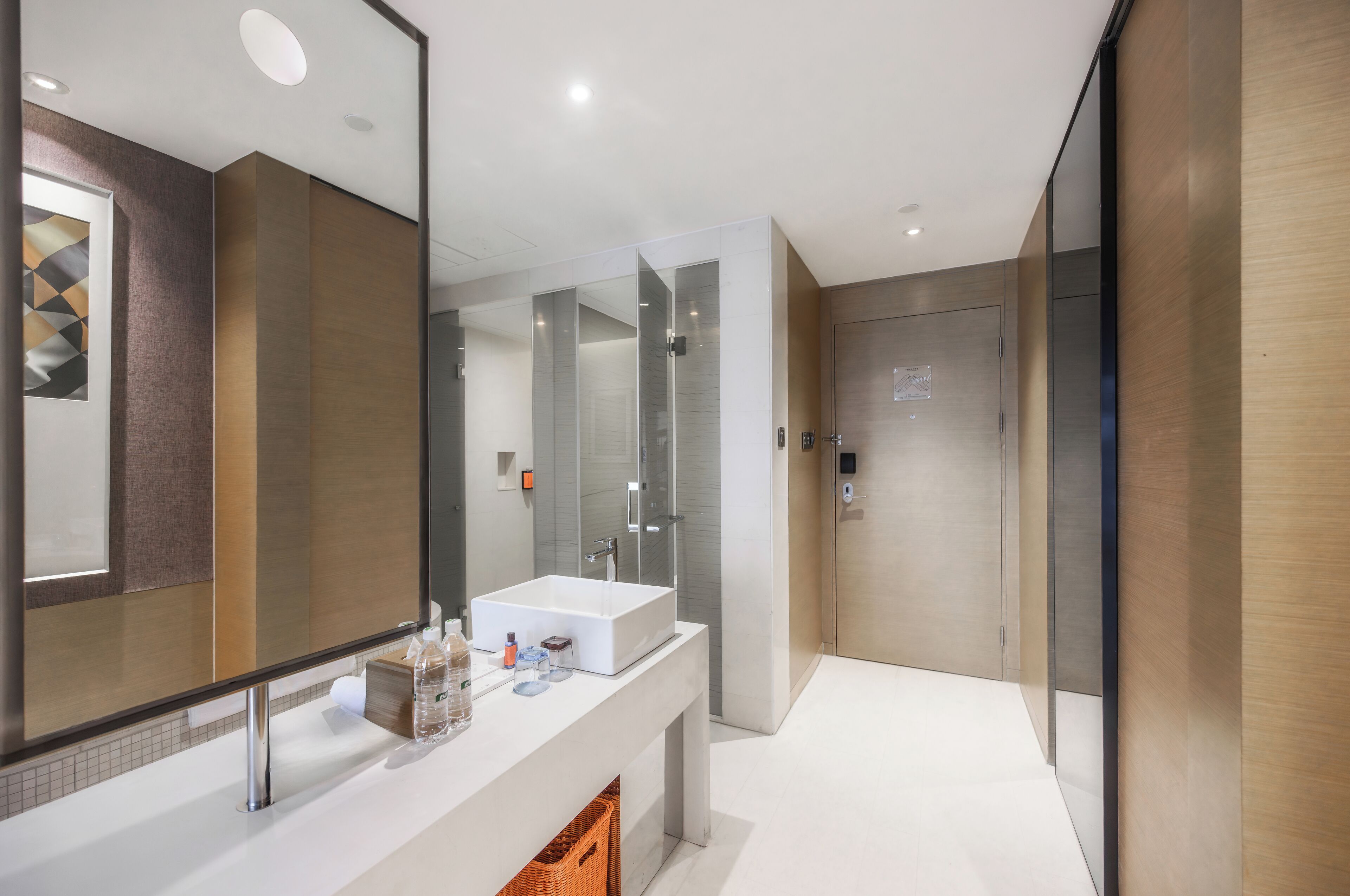 Un baño moderno con un espejo grande, un lavabo blanco y una cabina de ducha de cristal.