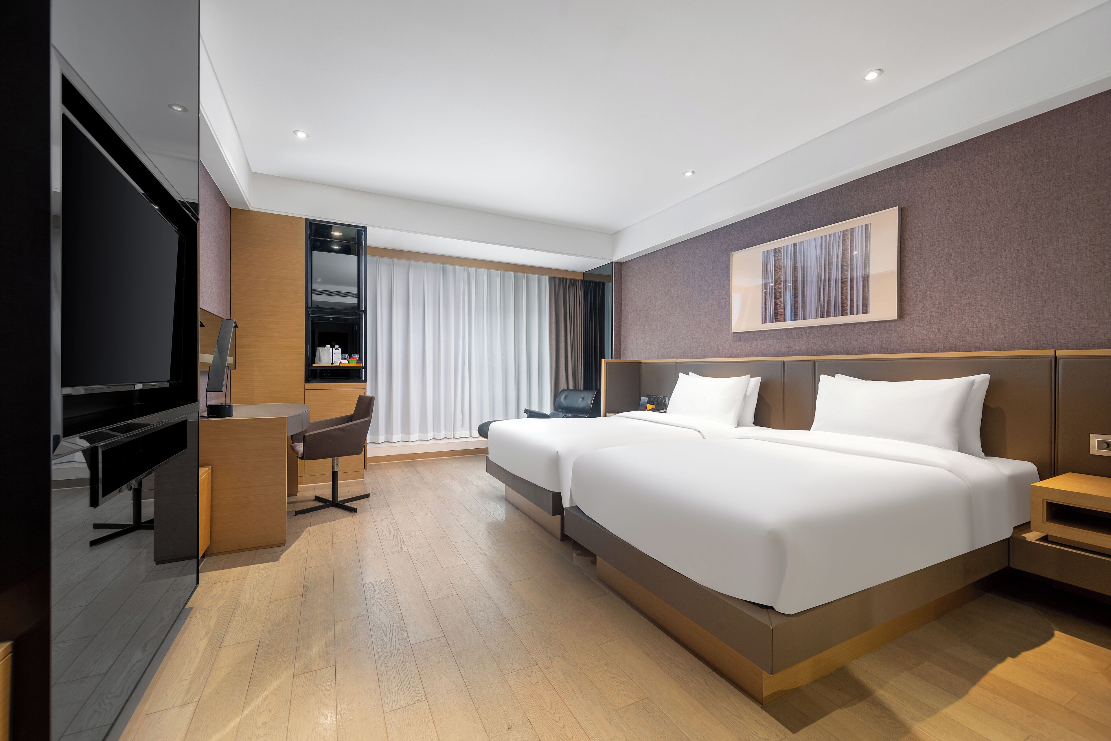 Quarto de hotel moderno com uma cama grande, uma mesa de trabalho e uma televisão.