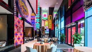 Ein modernes Restaurant mit Neonleuchten, runden Tischen und Stühlen.