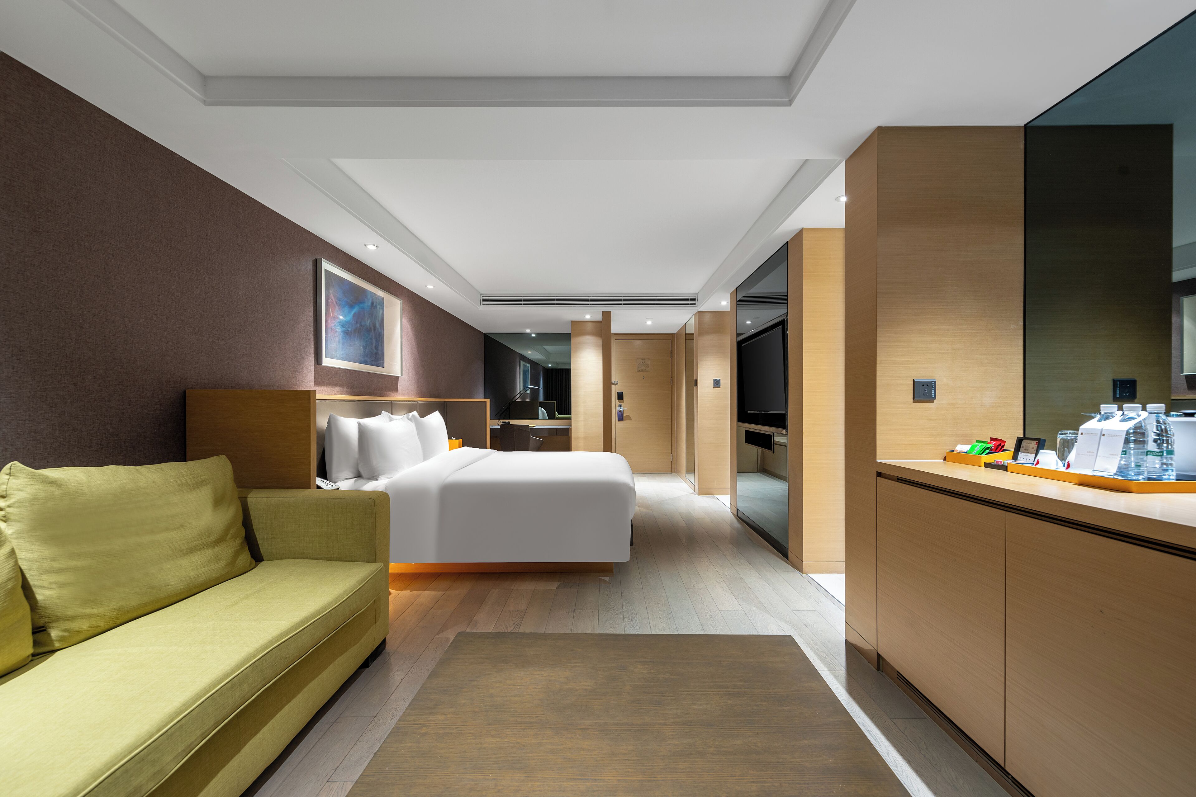Una habitación de hotel moderna con cama, sofá, escritorio y televisor.