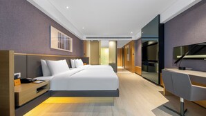 Ein modernes Hotelzimmer mit einem großen Bett, einem Schreibtisch und einem Flachbildfernseher.