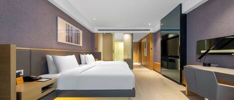 A modern hotel room with a large bed, a desk, and a flat-screen TV.