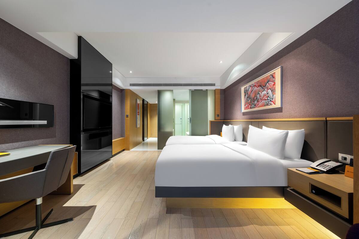 Une chambre d’hôtel moderne équipée d’un lit, d’un bureau et d’une télévision.