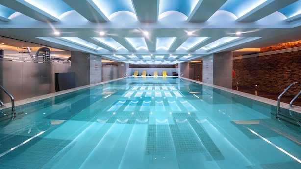 Ein modernes Hallenbad mit glasklarer Wasseroberfläche, einer Glaswand auf der einen Seite und einer Ziegelwand auf der anderen.