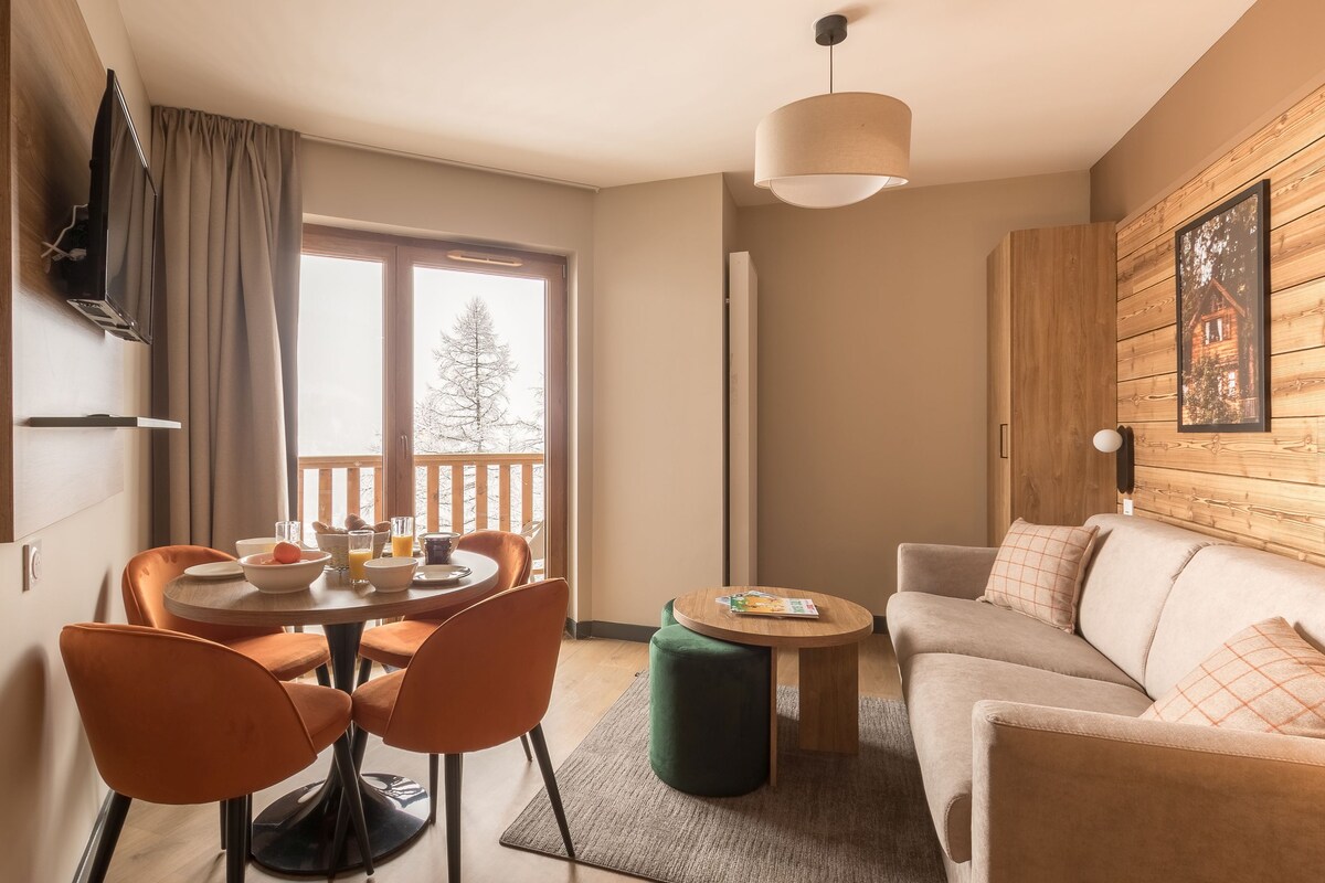 Ein modernes Wohnzimmer mit einer Couch, einem Esstisch mit Stühlen, einem Couchtisch und einem an der Wand montierten Fernseher.