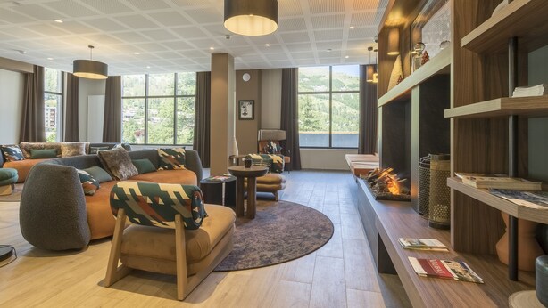 Ein modernes Wohnzimmer mit einer Eckcouch, einem runden Couchtisch und einem Kamin.