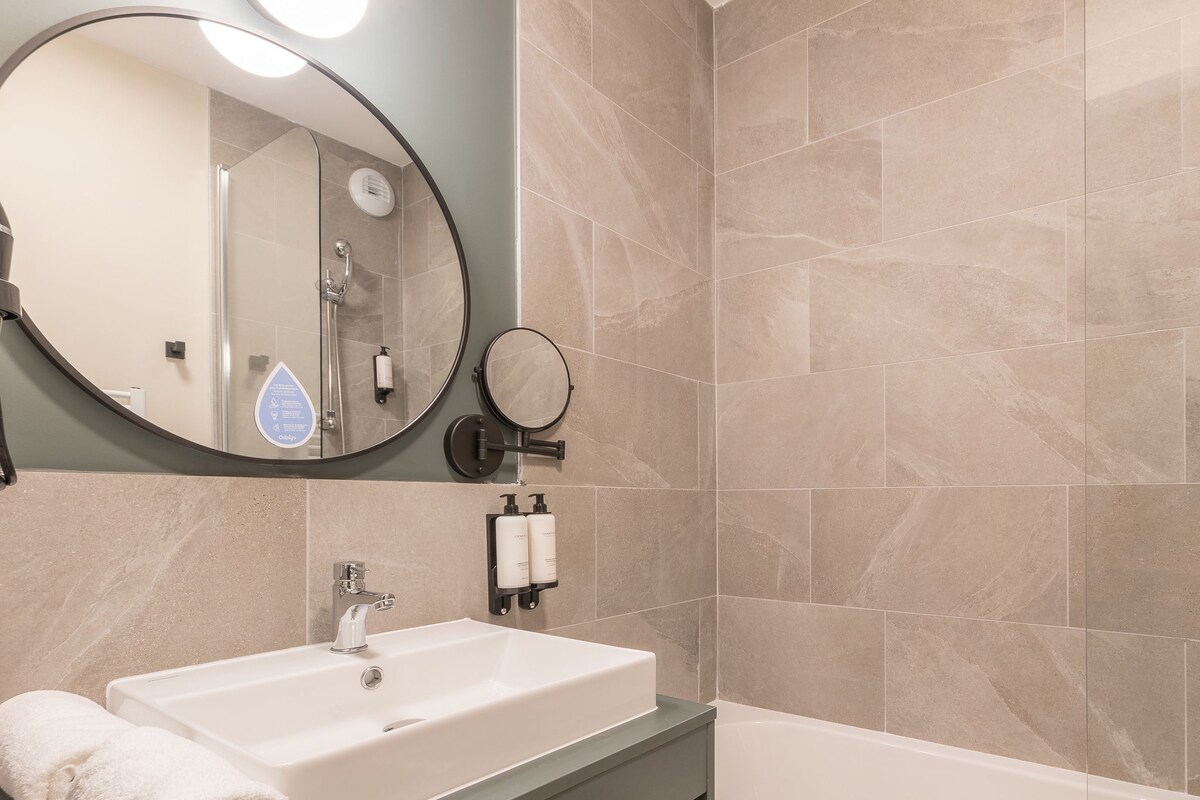 A bathroom with a white sink, a mirror, and a shower area.