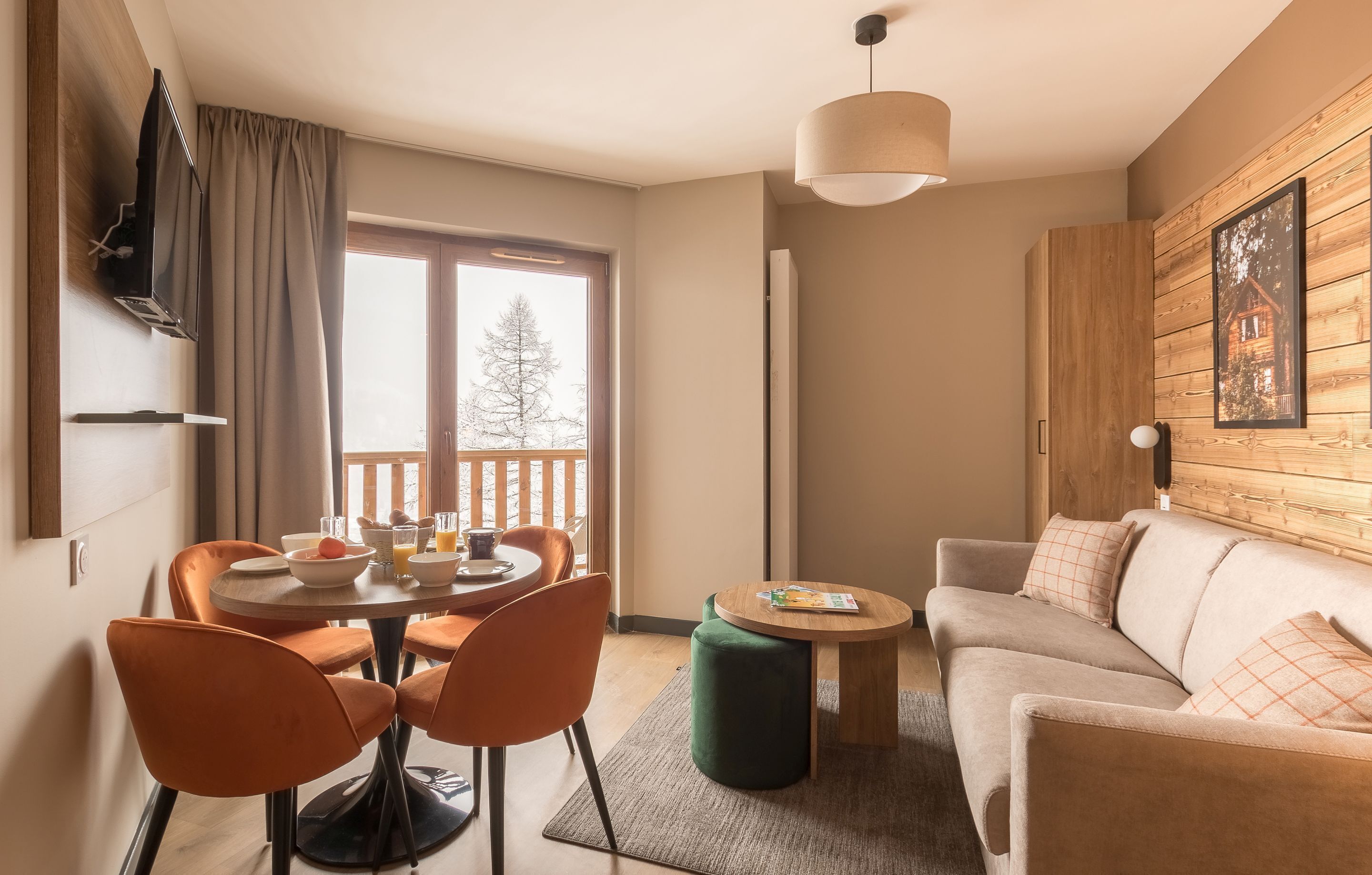 A modern living room with a sofa, a dining table with chairs, a coffee table, and a TV mounted on the wall.