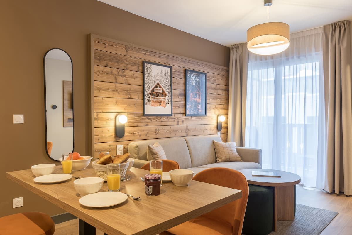 Un salon moderne avec un mur en bois, un canapé, une table à manger avec des aliments pour le petit-déjeuner et une grande fenêtre avec des rideaux.