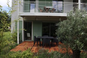 Enjoy the outdoors from the spacious balcony with a seating area, surrounded by a well-maintained garden and wooden deck.