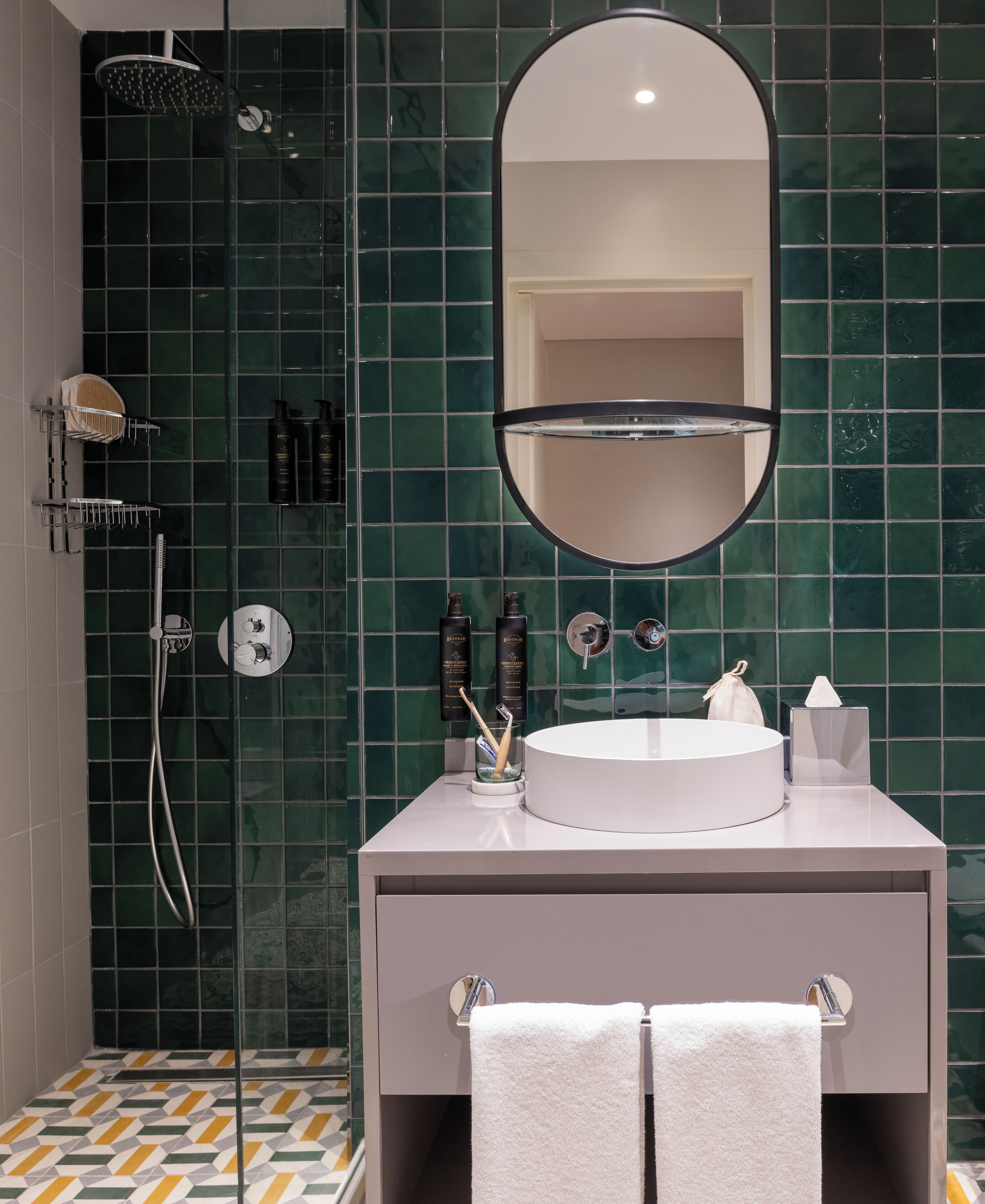 A modern bathroom with a round sink, a large mirror, and a shower area.