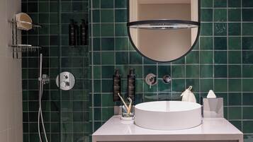 A modern bathroom with a round sink, a large mirror, and a shower area.