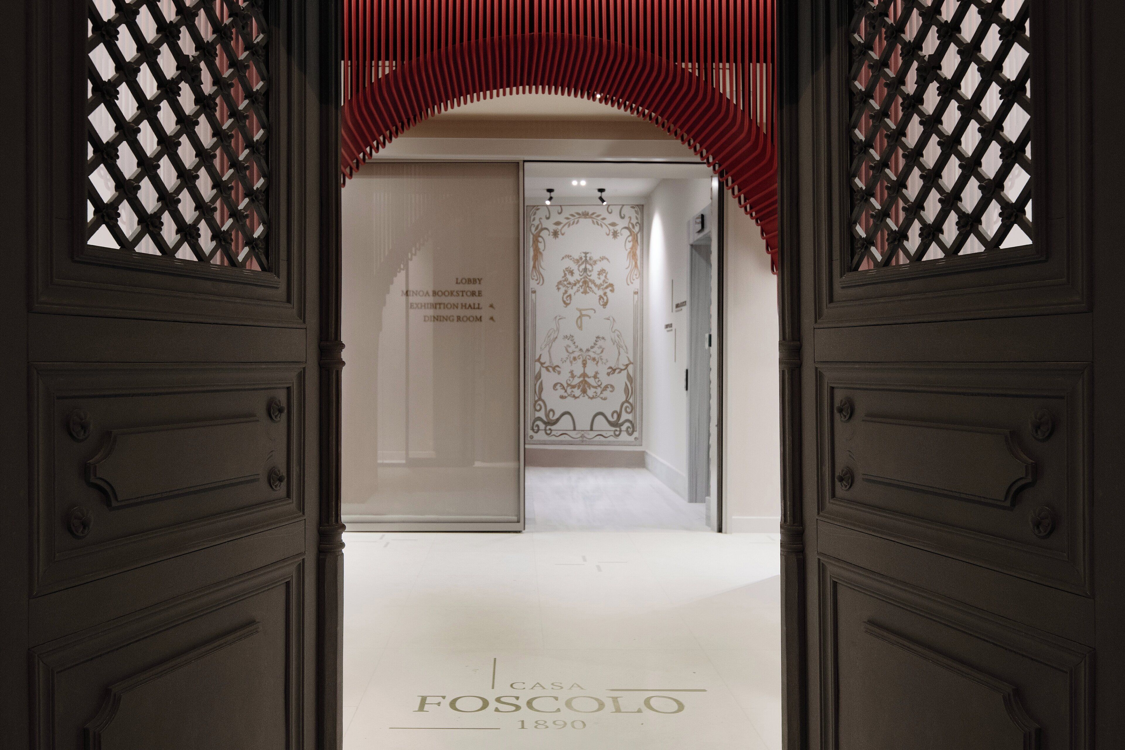 A hallway with a red archway leading to a room labeled "Casa Foscolo 1890".