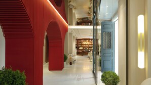 A modern interior with a red structural wall, a glass door, and a well-lit reading area with bookshelves. - Casa Foscolo Hotel, Istanbul, a Member of Design Hotels (Istanbul)