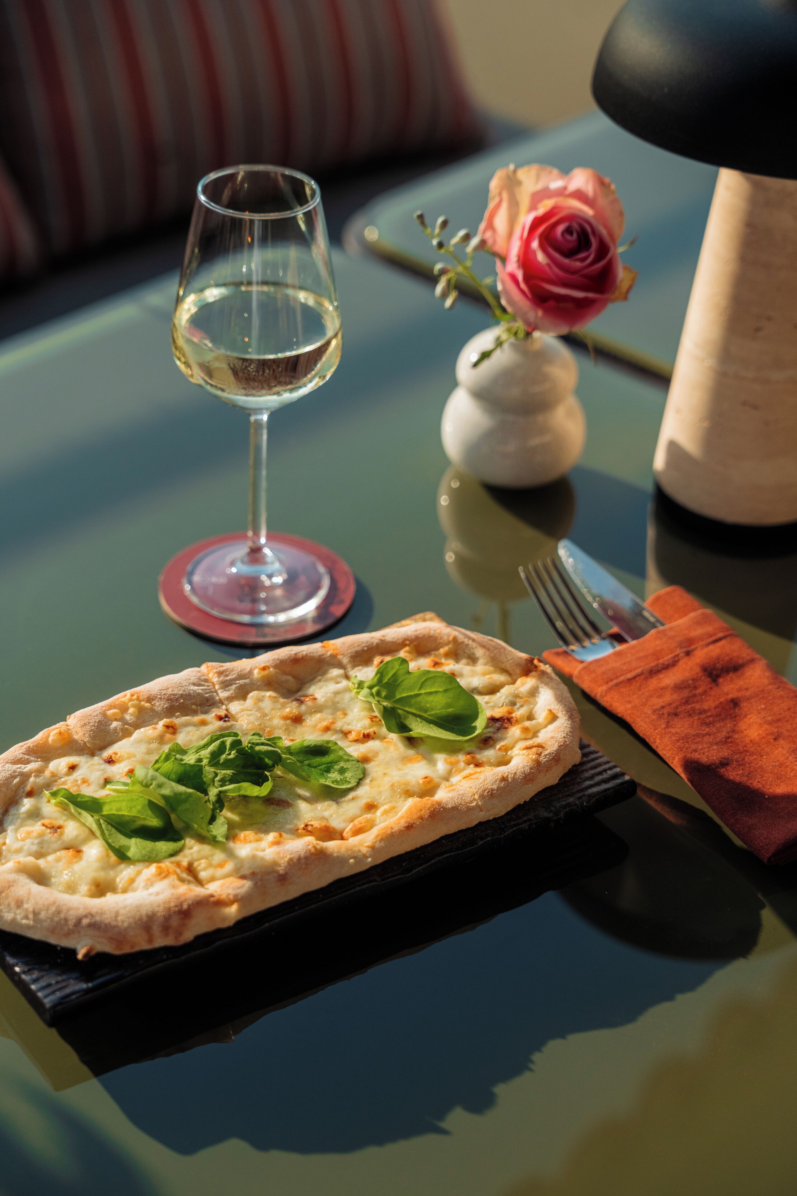 Une pizza et un verre de vin blanc sur une table.