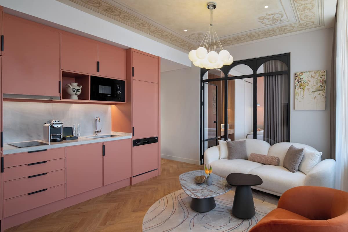 Eine moderne Küche mit rosa Schränken, einer weißen Arbeitsplatte und einer eingebauten Mikrowelle.