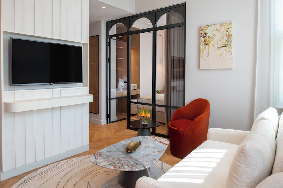 Ein modernes Wohnzimmer mit Flachbildfernseher an einer weißen Wand, einem roten Sessel, einem weißen Sofa und einem Marmor-Couchtisch.