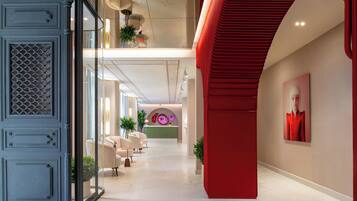 Eine moderne Hotellobby mit Glastrennwand, Sitzgelegenheiten und einer roten Akzentwand.