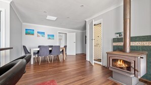 Un salon moderne avec un plancher en bois, un coin repas comprenant une table et des chaises, et un poêle à bois.