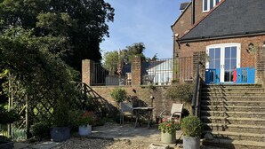 A courtyard with a brick building, a wooden bench, a table, and potted plants. - Lodge/ Kingbed/ Privg/ Petsok/ Freep/ Wifi (Dorchester)