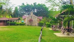 A stone building with a red roof, surrounded by green grass and trees. - Pacha Waterfront Nithi (Chuka)
