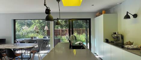 Een moderne keuken met een centraal eiland, grote ramen en een dakraam.