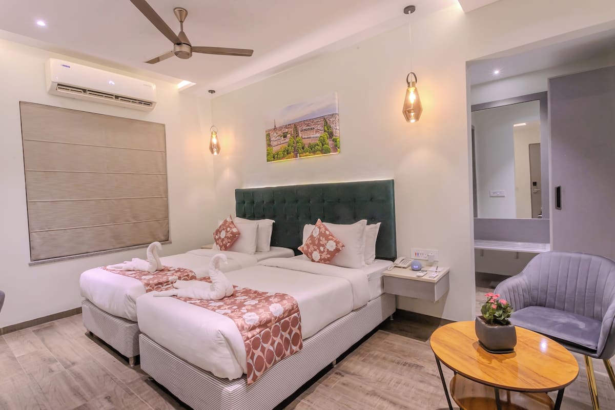 Une chambre d’hôtel avec un grand lit, une chaise, une petite table et un climatiseur fixé au mur.