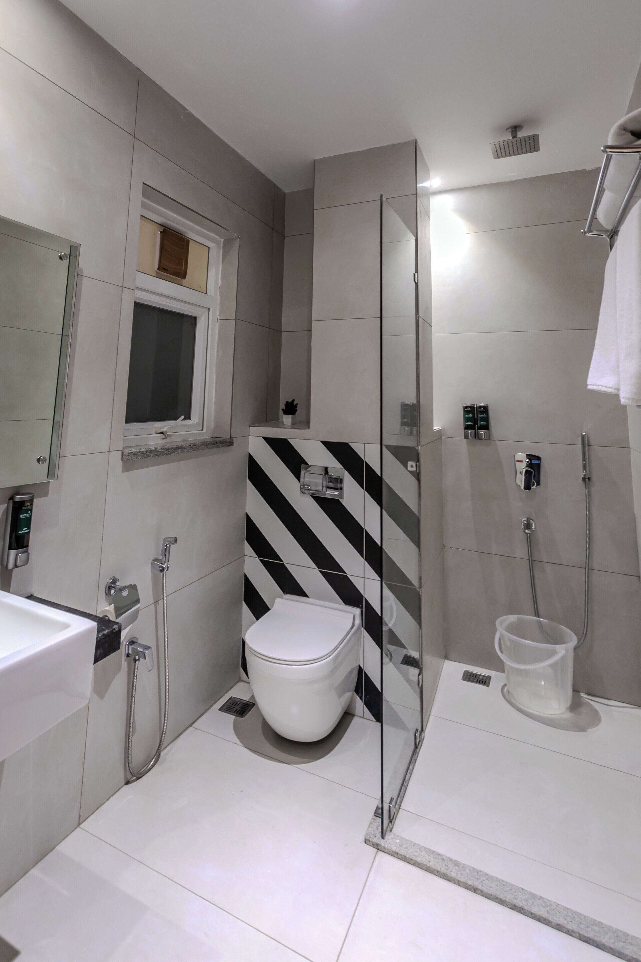 A modern bathroom with a toilet, a shower area with glass doors, and a sink.