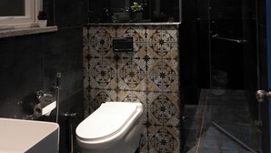 A modern bathroom with a toilet, sink, and shower. - World Inn (Visakhapatnam)