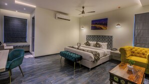 A modern bedroom with a bed, a sofa, a desk, and a chair. - World Inn (Visakhapatnam)
