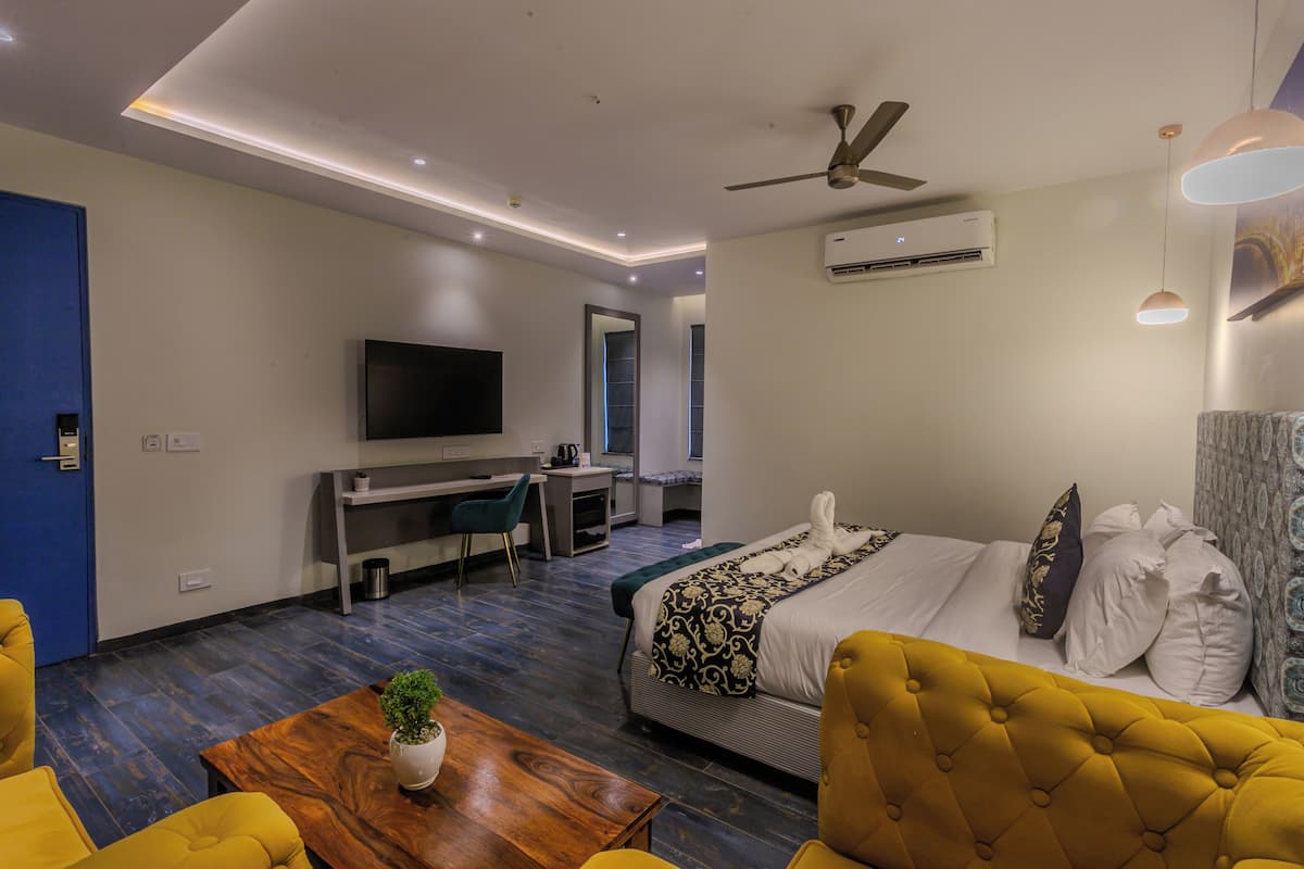 Une chambre d’hôtel moderne équipée d’un lit, d’un bureau, d’une télévision et d’un ventilateur de plafond.