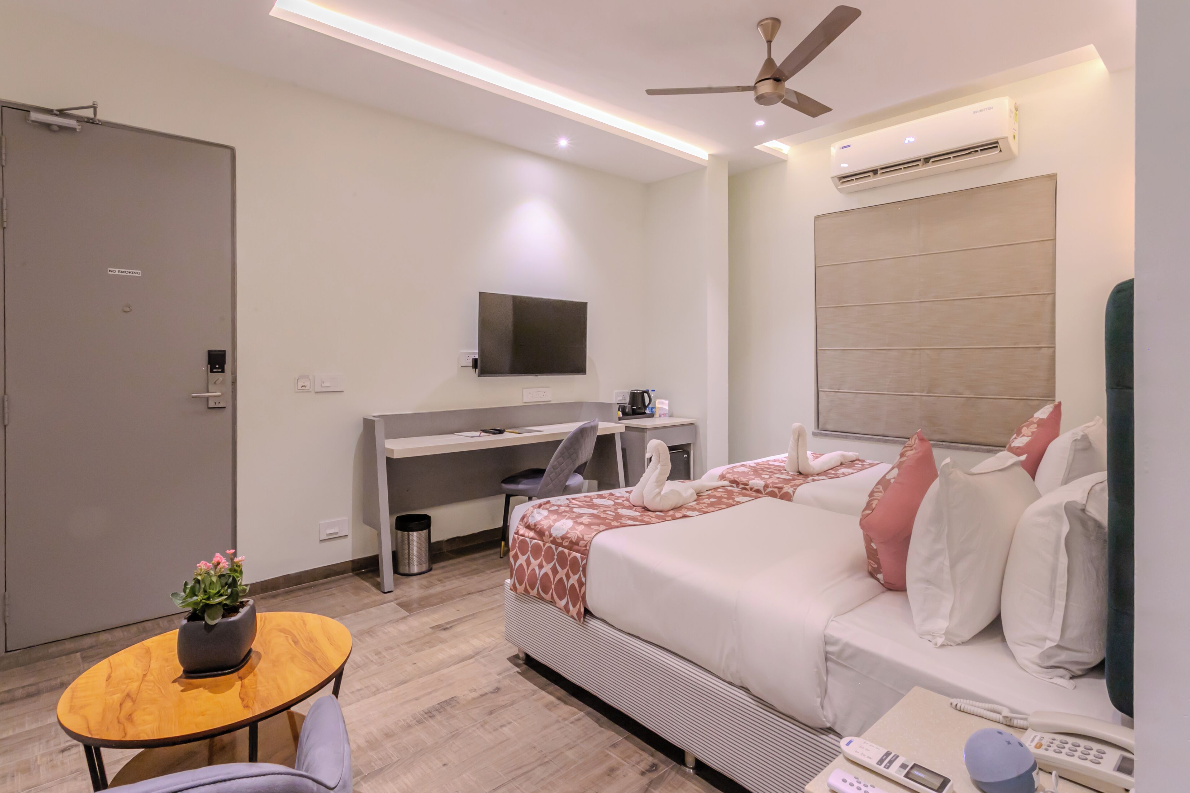 A modern hotel room with a bed, desk, and seating area.