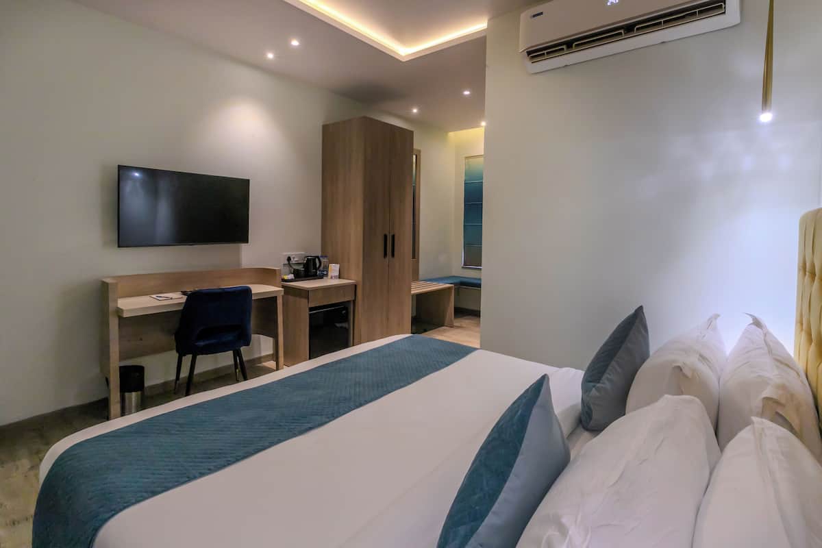 Une chambre d’hôtel comprenant un lit, un bureau, une chaise, une télévision et une armoire.