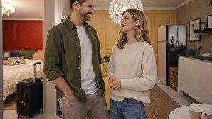 Habitació d'hotel moderna amb llit, escriptori i petita cuina.