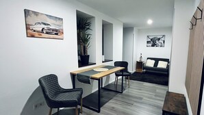 Un salon moderne avec un coin repas, comprenant une table en bois, deux chaises, un canapé et une plante en pot.