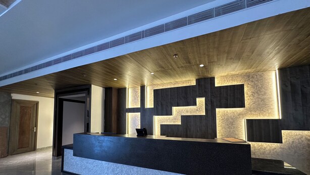 Un comptoir d’accueil au design moderne, doté d’un plan de travail foncé et agrémenté de motifs géométriques lumineux sur le mur situé derrière.