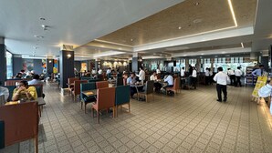 Un restaurant spacieux avec de hauts plafonds, un éclairage moderne et un sol carrelé.