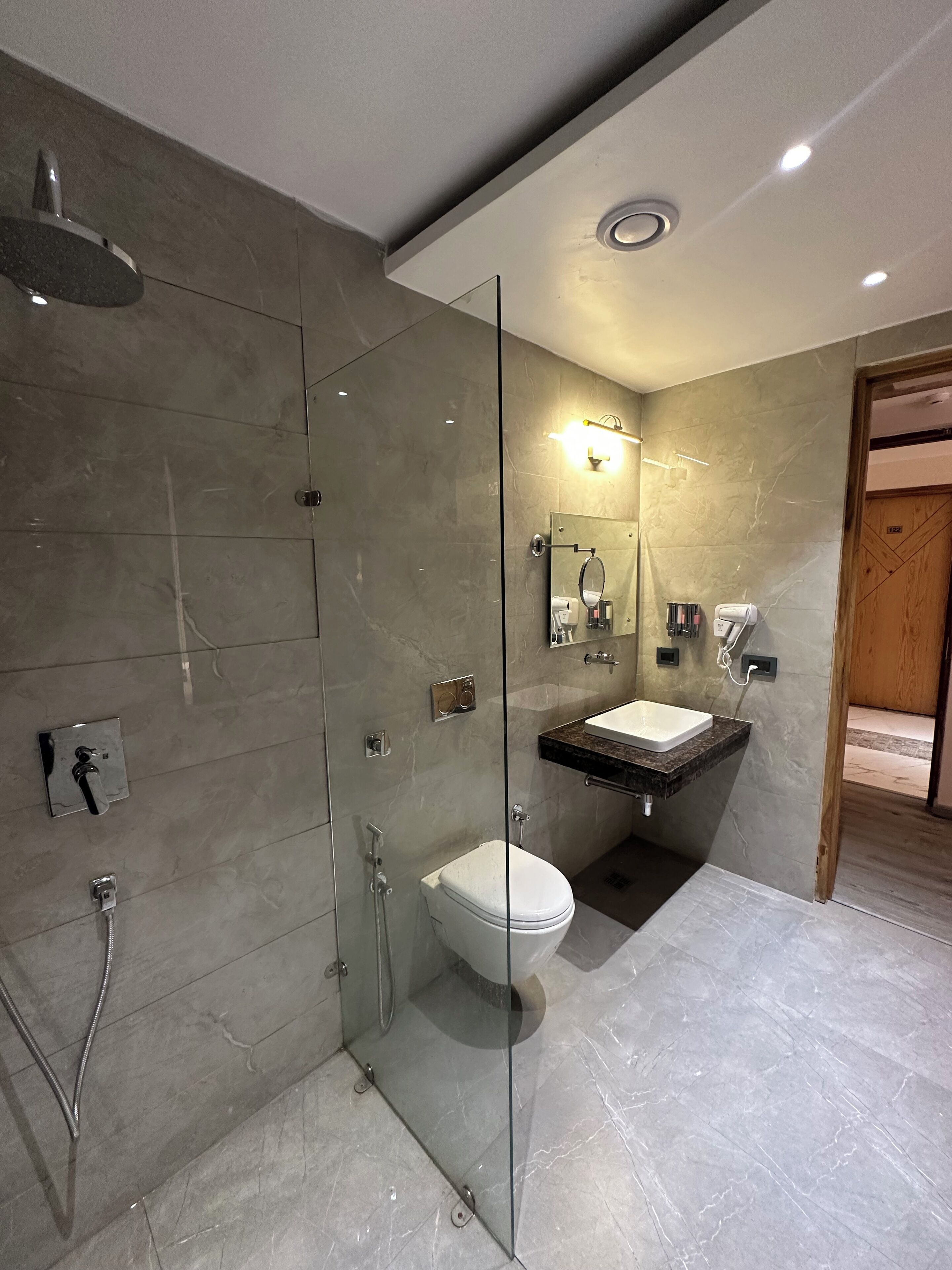 A modern bathroom with a glass-enclosed shower, a white toilet, and a vanity with a sink.