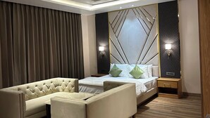 Une chambre à coucher moderne avec un canapé d’angle, un lit doté d’une tête de lit à motifs géométriques et un plancher en bois.