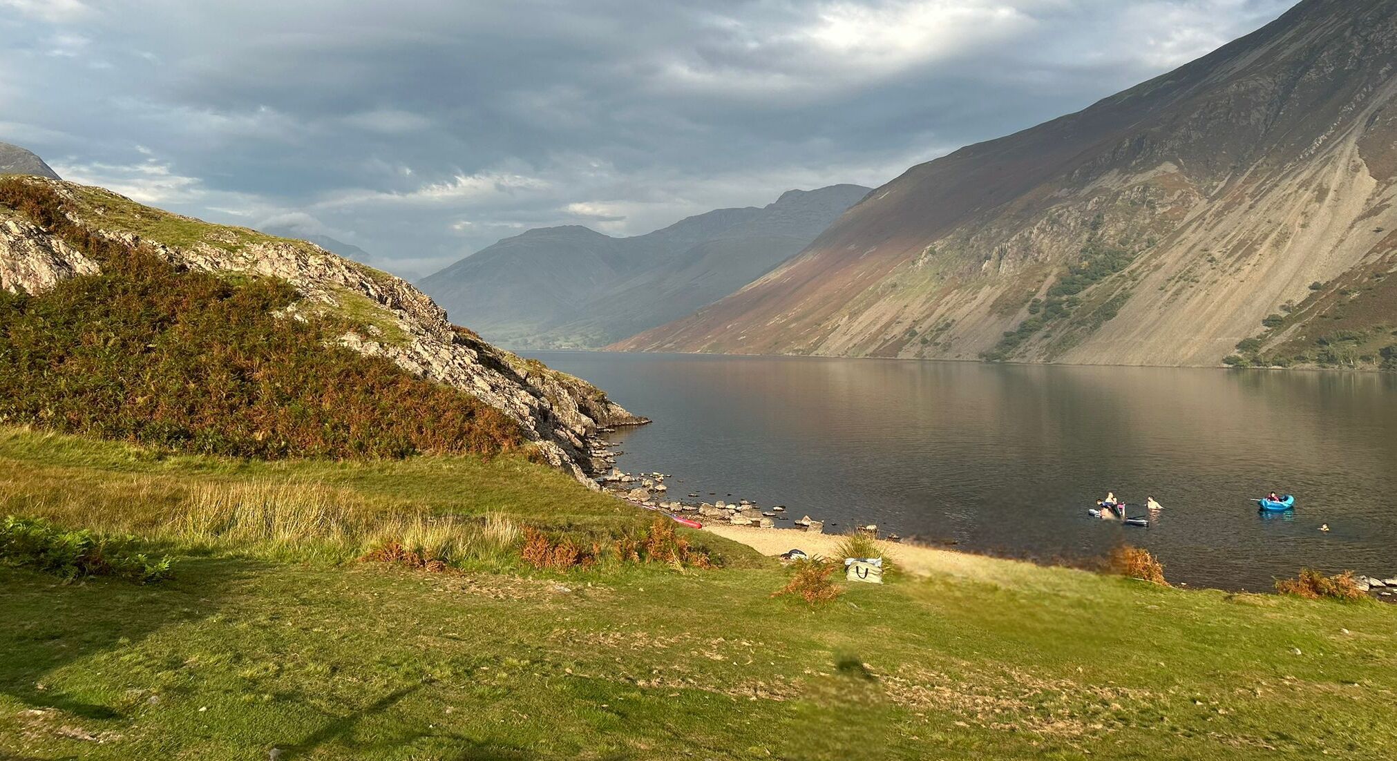A mountainous landscape with a lake, rocky shoreline, and boats on the water.