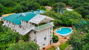 A two-story building with a green roof, a swimming pool, and lush greenery surrounding the property. - Room in Lodge - Luxury Suite in Boutique Lodge With Free Savannah Adventures 4x4 City Safari (Victoria Falls)