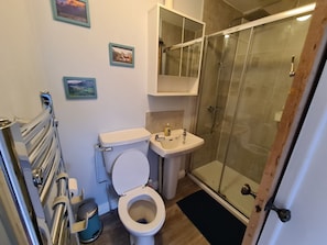 A bathroom with a toilet, sink, and glass shower enclosure. - Cozy Nottingham Apartment With Perfect Location (Nottingham)