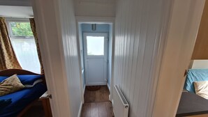A narrow hallway with a bed on the left, a door at the end, and a radiator on the right. - Cozy Nottingham Apartment With Perfect Location (Nottingham)