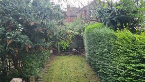 A garden with a wooden fence, a grassy area, and dense foliage. - Cozy Nottingham Apartment With Perfect Location (Nottingham)